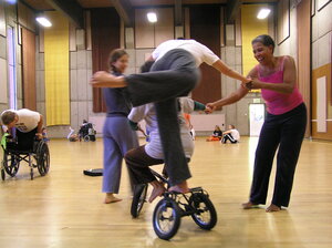 Mehrere TänzerInnen experimentieren mit einem Trike in einem Turnsaal